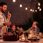 sfeervolle tuin met veel mensen om de tafel met lichtjes