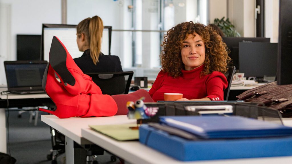 de mannenmaker vrouw in rode kleding met benen op bureau