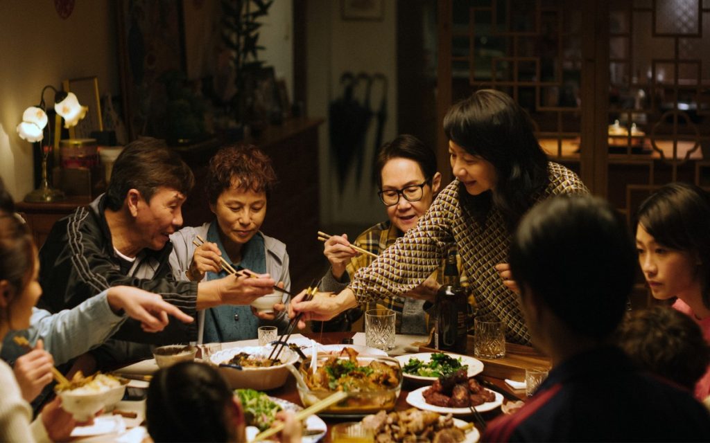 Veel mensen aan tafel eten. FIlm over lesbische relatie