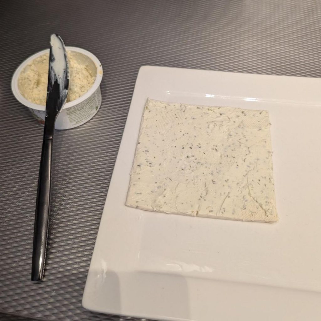 kruidenkaas op de bladerdeeg smeren